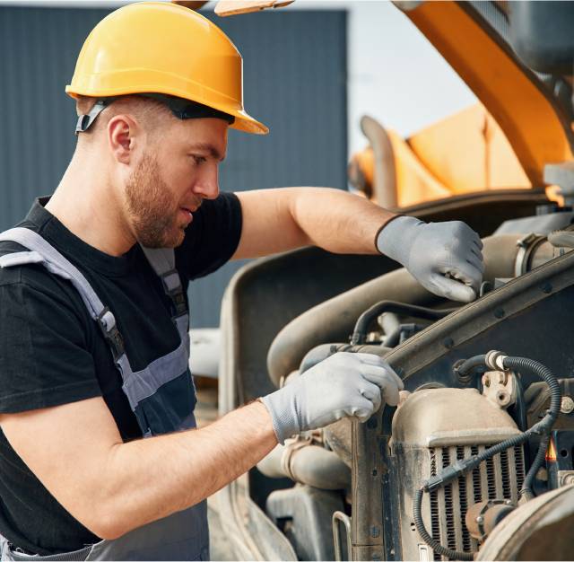 Technician in gloves repairing heavy equipment engine parts