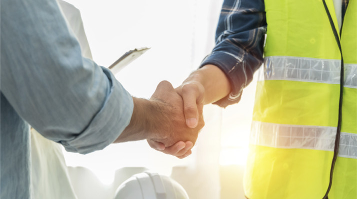 Business handshake between a client and a worker in a safety vest
