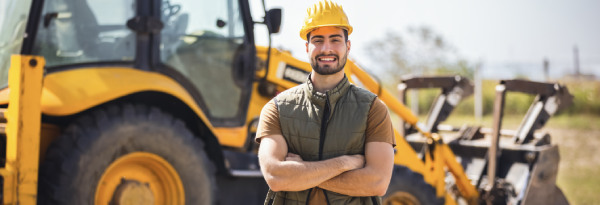 Equipment operator standing in front of a yellow backhoe loader